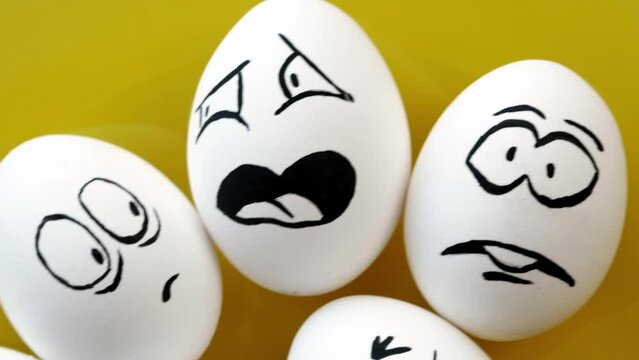 Boiled white eggs with funny emotional faces on a yellow plate. Fear, anger, contempt, laughter, joy, surprise, annoyance. Easter.