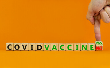 Covid vaccine yes or no symbol. Doctor turns cubes and changes words covid vaccine no to covid vaccine yes. Beautiful orange background, copy space. Covid-19 vaccine yes and medical concept.
