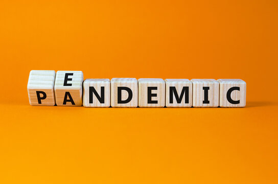 Covid-19 pandemic or endemic symbol. Turned wooden cubes and changed the concept word pandemic to endemic. Beautiful orange background copy space. Medical Covid-19 pandemic or endemic concept.