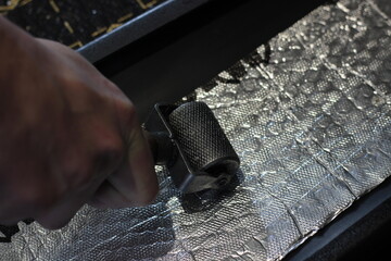 Working hands roll soundproofing material on the car parts.A worker glues sound insulation material...