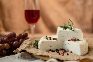 Goat cheese, grapes and wine lie on a wooden table. Cheese at home.