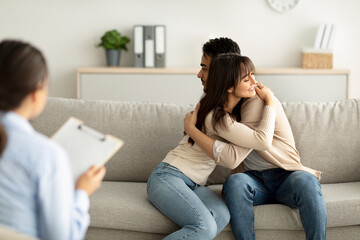 Loving arab couple hugging in counselor's office after successful marital therapy, being grateful...