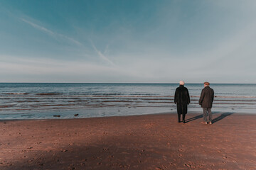 Elderly couple walking along the shore of a calm sea (976)