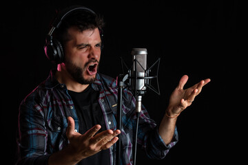 Hombre cantor grabando su voz con microfono de condensador y auriculares