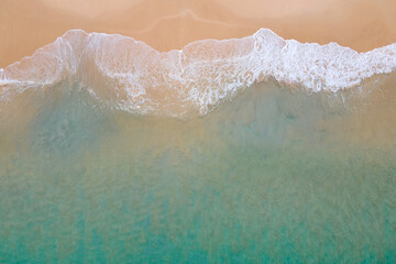 Fototapeta na wymiar Aerial view of turquoise ocean wave reaching the coastline. Beautiful tropical beach from top view. Andaman sea in Thailand. Summer holiday vacation concept