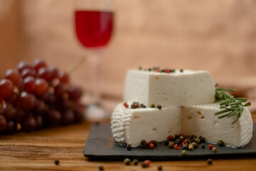 Goat cheese, grapes and wine lie on a wooden table. Cheese at home.