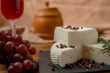 Goat cheese, grapes and wine lie on a wooden table. Cheese at home.