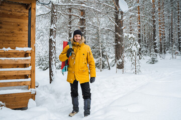 A traveler in bright clothes walks through a forest thicket through a blizzard, Snowy forest and rocks. Climbing the mountain in winter. Survival in the wild.
