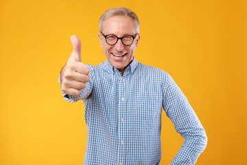 Happy mature guy gesturing thumbs up and smiling