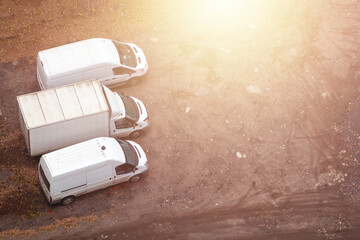 Top view of three white truck vans parked on warehouse area. Copy space. Yellow glow.