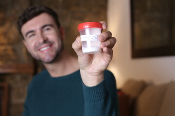 Healthy man holding sperm sample in plastic container