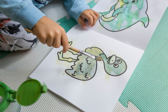 Hands Of A Child Coloring With Brush An Emu In Water Book