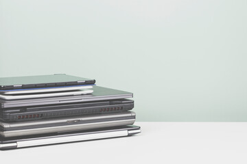 Pile of old used laptop computers for recycling on white table. Planned obsolescence, e-waste, electronic waste for reuse and recycle concept
