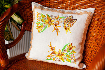 White decorative pillow with embroidery in the form of flowers and butterflies.