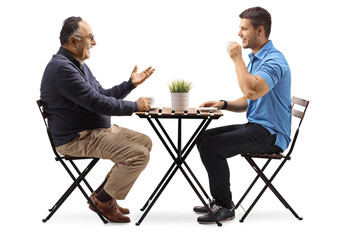 Obraz premium Young and mature man seated at a table and having a coffee