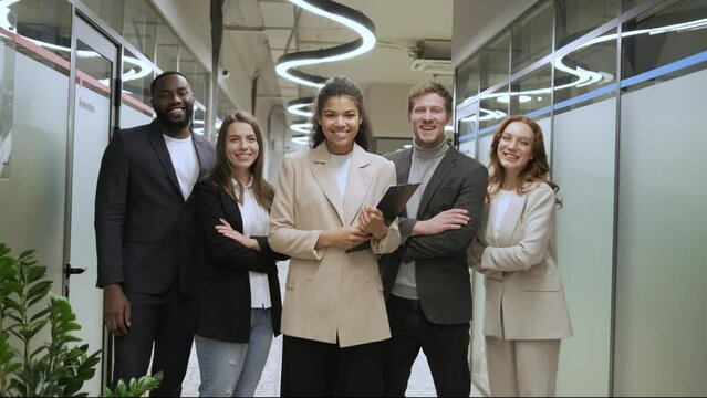 standing in row smiling diverse team employees in the office looking at camera. Happy young multiethnic corporate staff