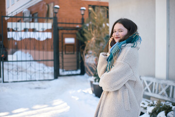 Smiling young woman is talking on the smartphone, snow around her