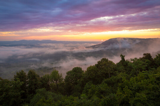 Colorful morning sunrise with golden glowing fog clouds over mountains at Arkansas Grand Canyon Scenic Point Overlook 