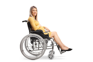 Fototapeta na wymiar Full length profile shot of a pregnant woman sitting in a wheelchair and looking at camera