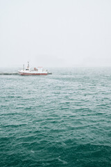 Ship on rippled sea with pier in fog