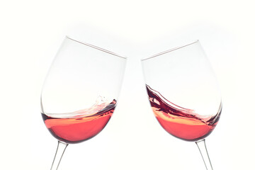 Two glasses of rose wine toasting and splashing on white background.