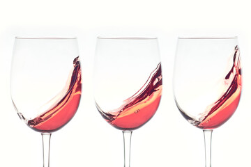 Three glasses of rose wine splashing on white background.
