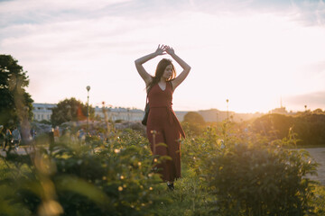 Portrait of a beautiful young woman in the park at sunset in summer.