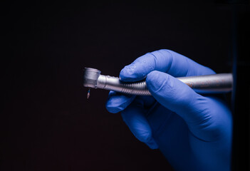 a dental tip and a metal bur in dentistry treats caries a blue gloved hand holds © Natalia Palii