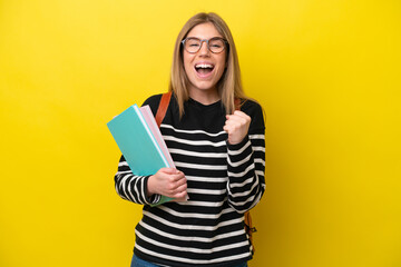 Young student woman isolated on yellow background background celebrating a victory in winner position