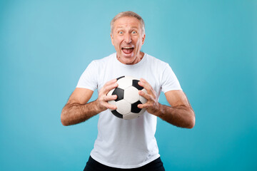Mature man posing with soccer ball on blue background