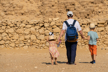 Father and children walk in front of the Chephren pyramid on the Giza plateau.