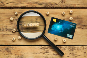 Word Fraud of cubes with letters, credit card and magnifying glass on wooden background, flat lay