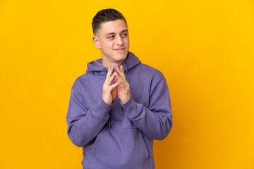 Young caucasian man isolated on yellow background scheming something