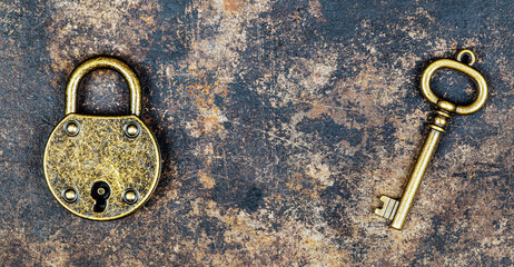 Old vintage key and padlock on a rusty grunge metal background. Escape room game concept.