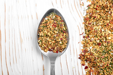 A mixture of various spices in a spoon on a white wooden background with copy space.