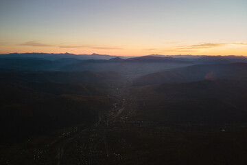 Aerial view of dark mountain hills at sunset. Hazy peaks and misty valleys in evening