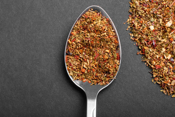 A mixture of various spices in a spoon on a black background with copy space.