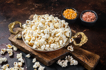Obraz na płótnie Canvas Prepared salty popcorn in a skillet and corn kernel. Dark background. Top view