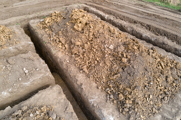 Fototapeta premium Dug out trench for building works of new house concrete foundation on construction site