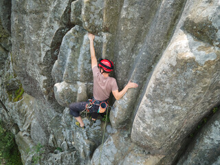 Strong male climber climbing steep wall of rocky mountain. Sportsman overcoming difficult route. Engaging in extreme sports hobby concept