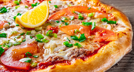 delicious pizza with tuna fish and lemon on wooden background