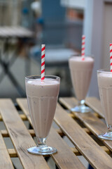 Chocolate milkshake on a wooden table in a summer outdoor cafe.