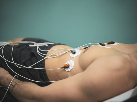 doctor with electrocardiogram equipment doing cardiogram test to male patient in hospital clinic