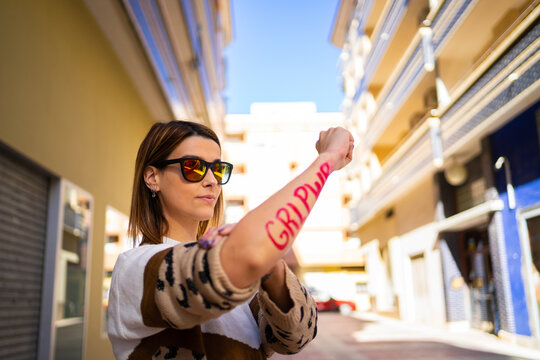 A young woman showing the letters "GLR PWR" written on her arm as a symbol of women's power as she raises her fist.