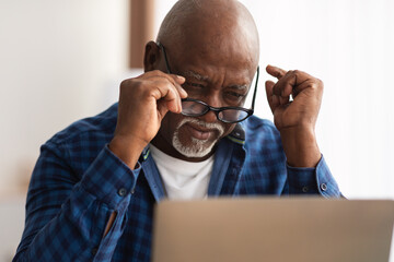 Senior Black Man Squinting Eyes Taking Off Eyeglasses Indoor - obrazy, fototapety, plakaty