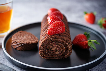 Chocolate cake roll with fresh strawberries in a plate