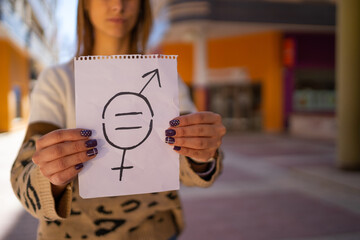 A young woman holds a paper with a gender equality symbol.