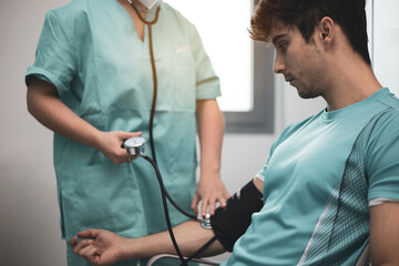 Doctor taking blood pressure and pulse on the arm of a patient in the clinic