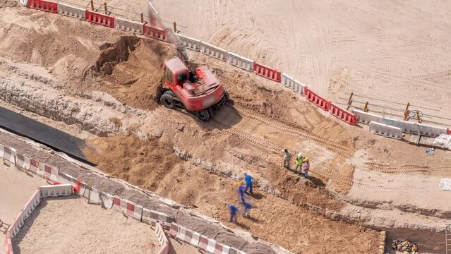 Group of worker and red excavator diging water drainage at construction site aerial timelapse.