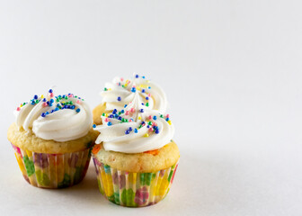Three mini confetti cupcakes on a white background with white background.  Decorated with Easter...